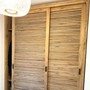 Teak Massivholz Schrank Manacor mit zwei  Schiebetueren, Schrank mit Lamellen Shutter in mediterraner Optik, Schrank aus massivem Teak in der MOEBEL KOLONIE Farbe Roh, gefertigt vom Schreiner in Handarbeit in unserer Manufaktur, Schrank nach Mass aus Massivholz Teak Muenchen, Dekoration Hänge Leuchte in Korb Optik